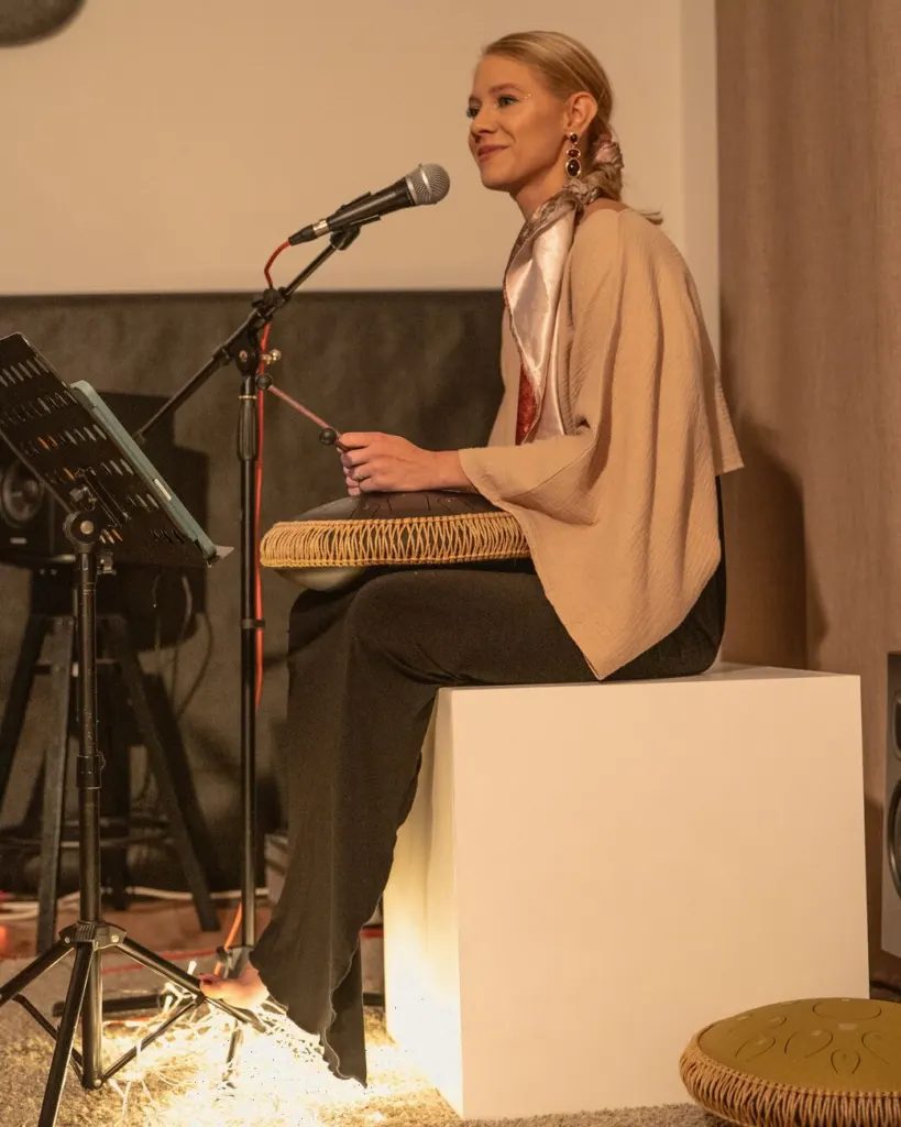 Dorota Wolniewicz śpiewa, siedząc z tongue drumem na kolanach. Przed nią mikrofon, u stóp ciepłe światło lampek.